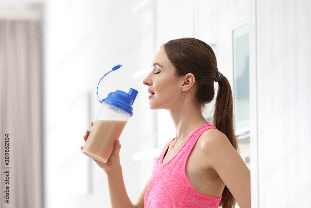 Athletic young woman drinking protein shake in kitchen Athletic young woman drinking protein shake in kitchen