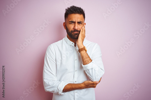 Young indian businessman wearing elegant shirt standing over isolated pink background thinking looking tired and bored with depression problems with crossed arms.