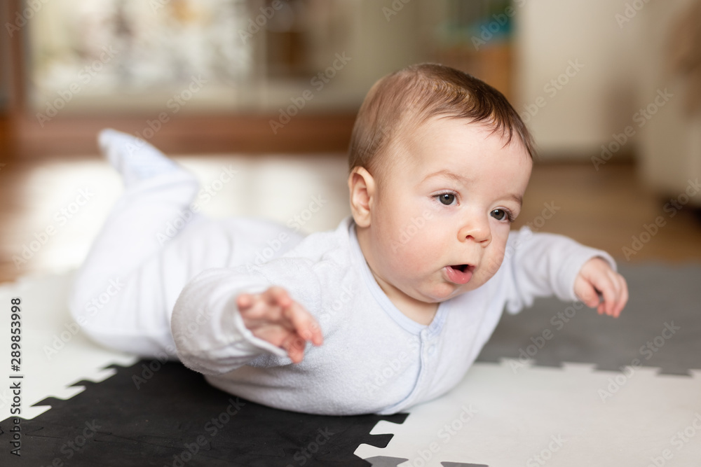 Fototapeta premium Beautiful cute little baby is lying on the floor. Boy. Love. Motherhood. Happiness. House.