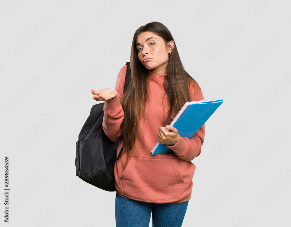 Young student woman holding notebooks unhappy for not understand something over isolated grey background Young student woman holding notebooks unhappy for not understand something over isolated grey background