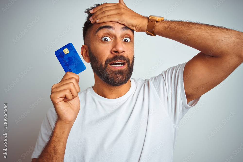 Young indian customer man holding credit card standing over isolated ...