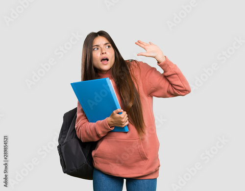 Young student woman holding notebooks nervous and scared over isolated grey background