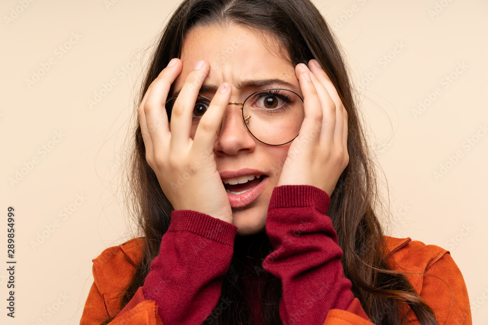 Teenager girl with coat covering eyes and looking through fingers Teenager girl with coat covering eyes and looking through fingers