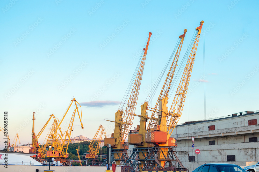 Old port cargo cranes against the evening blue sky