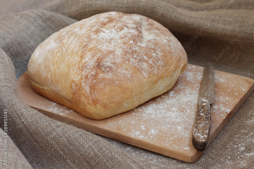 Fresh bread on a wooden board with a knife. Top view with space for your text. Fresh bakery