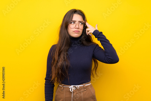 Teenager girl over isolated yellow wall with problems making suicide gesture