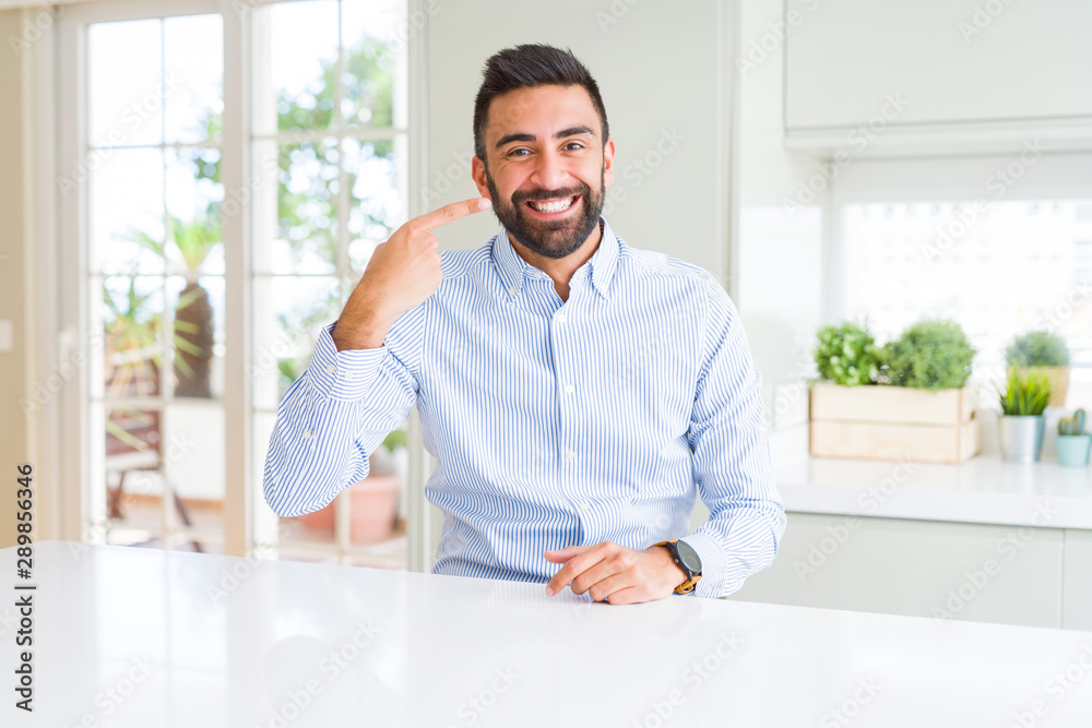 Handsome hispanic business man Pointing with hand finger to face and nose, smiling cheerful