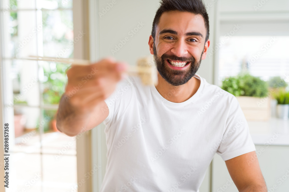 Handsome man smiling happy enjoying eating fresh colorful asian sushi using chopsticks Handsome man smiling happy enjoying eating fresh colorful asian sushi using chopsticks