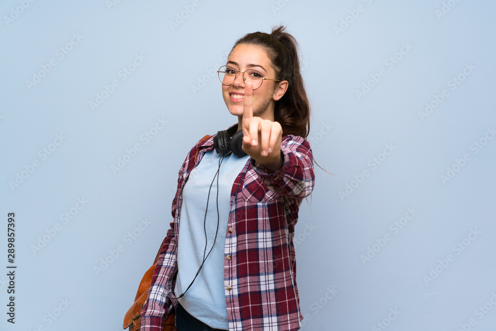Teenager student girl over isolated blue wall showing and lifting a finger Teenager student girl over isolated blue wall showing and lifting a finger