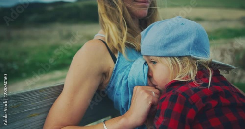 Mother breastfeeding toddler on bench in nature