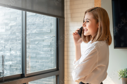 Asian women beautiful charming smiling and talking on the phone in her office. Free Download Asian women beautiful charming smiling and talking on the phone in her office. - GFXLoad