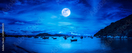 Beautiful panorama nature landscape. Beach by the sea with mountains and full moon at nighttime.
