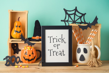 Halloween holiday concept with photo frame, jack o lantern cup, candy corn and decorations on wooden table