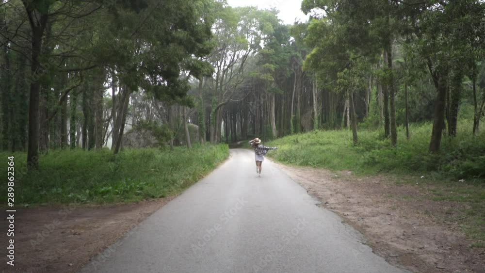 Young lady traveler running in magical forest in wonderland. Tall green trees, fairytale plants and huge stones. Sintra. Young lady traveler running in magical forest in wonderland. Tall green trees, fairytale plants and huge stones. Sintra.