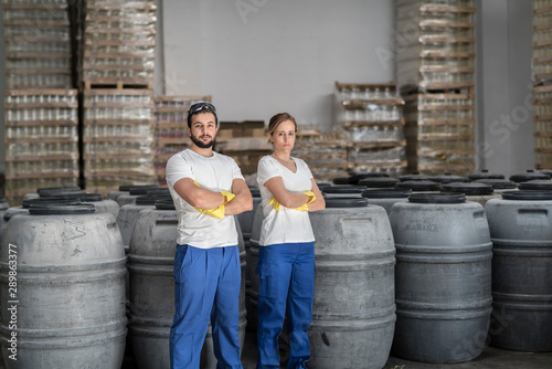 Couple of workers posing in olives factory looking at camera with crossed arms