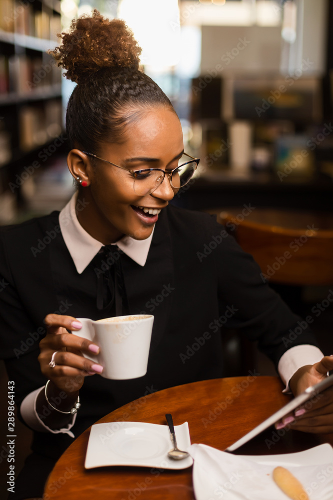 Black african american young yoman drinking coffee and using a tablet