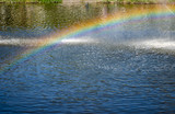 Rainbow spray fountain on the background of the river.