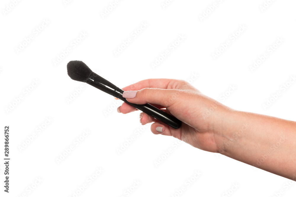Cosmetic brush for makeup in a female hand isolated on white background. Cosmetic brush for makeup in a female hand isolated on white background.