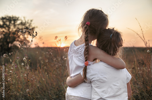 Two little sisters in a field at sunset. photo