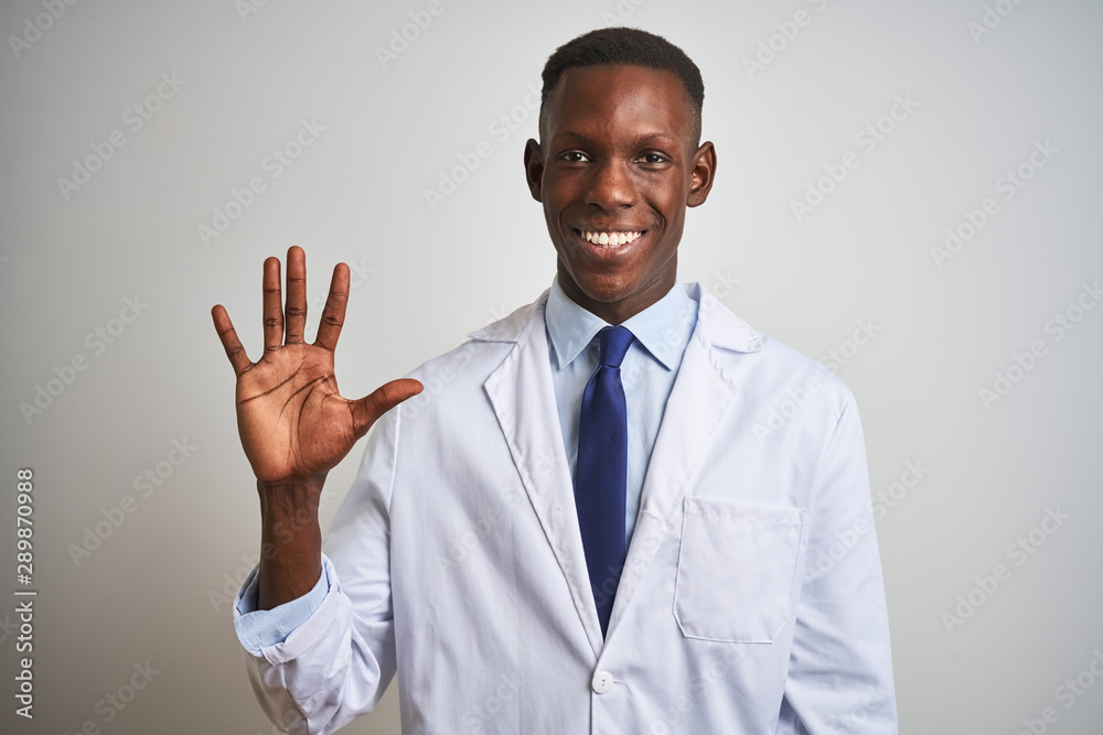 Young african american doctor man wearing coat standing over isolated white background showing and pointing up with fingers number five while smiling confident and happy. Young african american doctor man wearing coat standing over isolated white background showing and pointing up with fingers number five while smiling confident and happy.