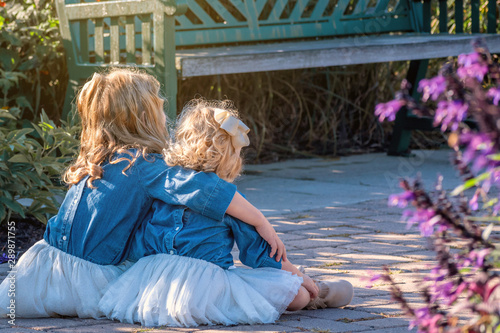 Two young girls with blond hair are enjoying a flower garden photo