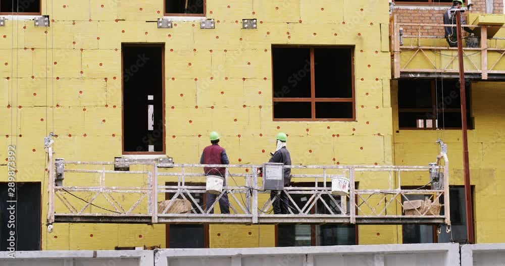 workers at a construction site insulate the walls of a multi-storey building