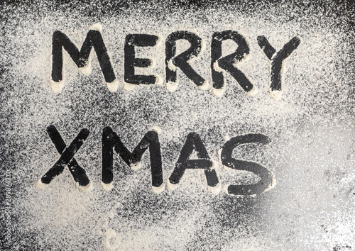 the words Merry Xmas is written on a baking tray sprinkled with powdered sugar or flour