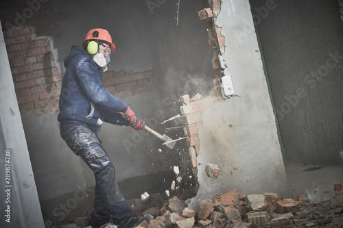 demolition work and rearrangement. worker with sledgehammer destroying wall