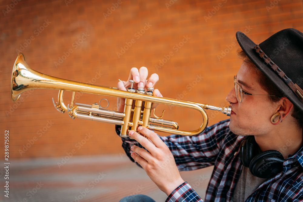 Obraz premium young man wearing a plaid long sleeves shirt Blowing Trumpet