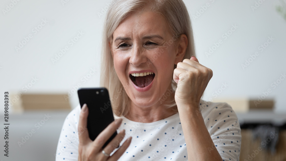 Close up excited older woman shouting, using phone, celebrating success - obrazy, fototapety, plakaty 