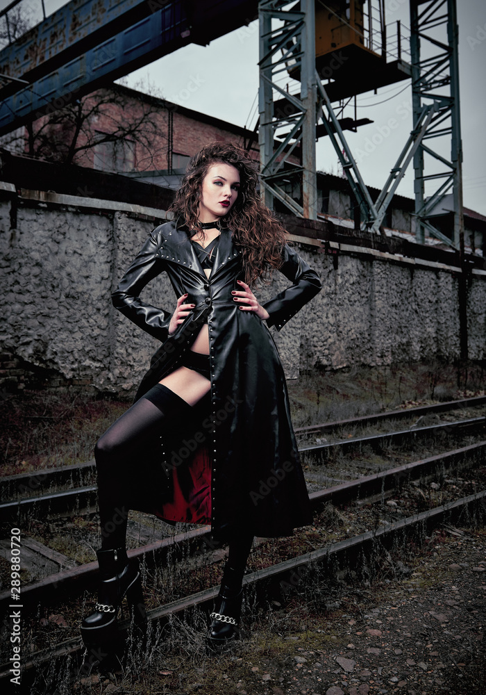 Fashion shot: portrait of sexy cute goth girl (informal model) in leather  coat, stockings and lingerie standing at railroad (industrial area) Stock  Photo | Adobe Stock