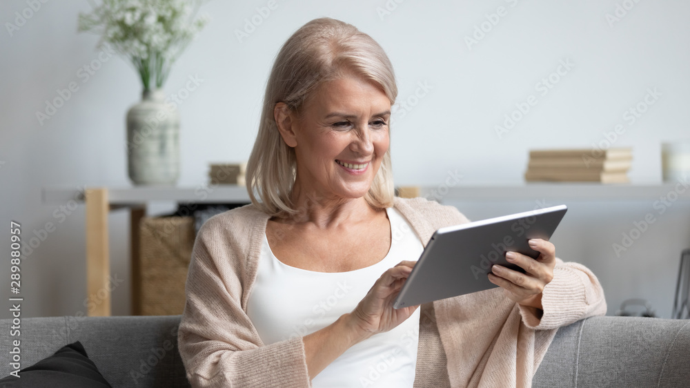 Smiling mature woman using computer tablet apps, having fun Smiling mature woman using computer tablet apps, having fun