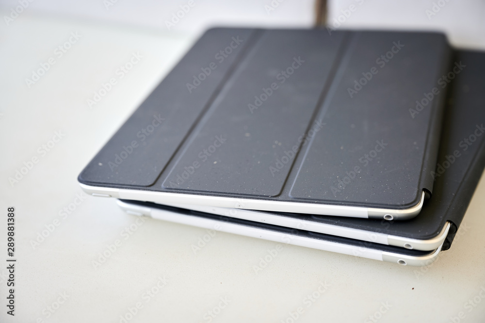 three tablets with covers on a white table
