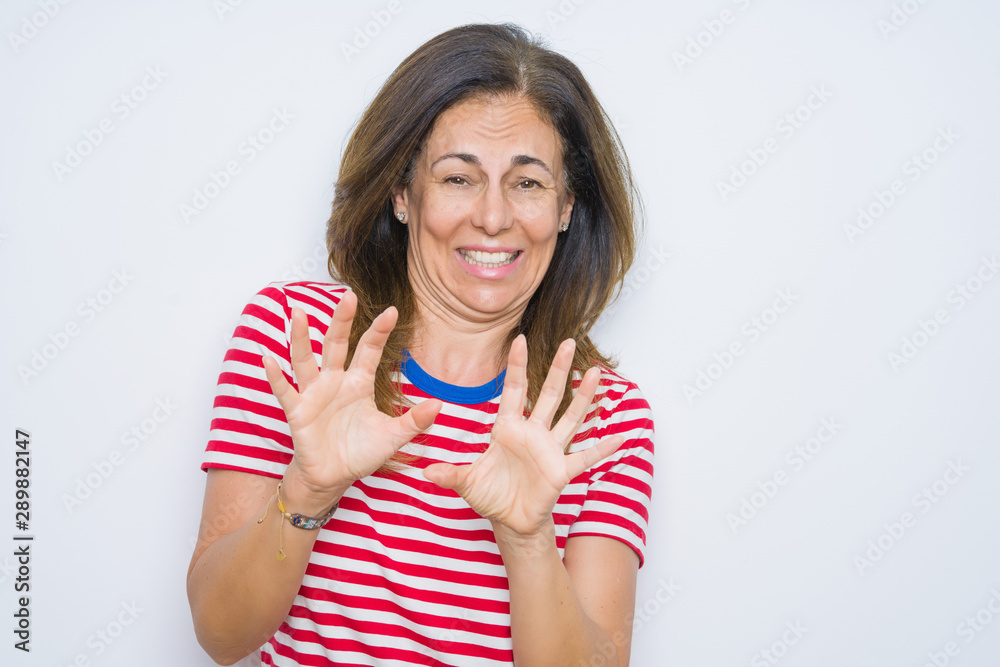 Middle age senior woman standing over white isolated background disgusted expression, displeased and fearful doing disgust face because aversion reaction. With hands raised. Annoying concept. Middle age senior woman standing over white isolated background disgusted expression, displeased and fearful doing disgust face because aversion reaction. With hands raised. Annoying concept.