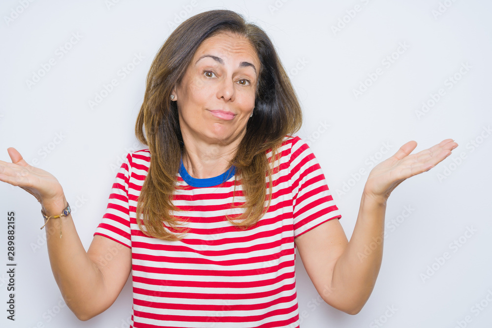 Middle age senior woman standing over white isolated background clueless and confused expression with arms and hands raised. Doubt concept. Middle age senior woman standing over white isolated background clueless and confused expression with arms and hands raised. Doubt concept.