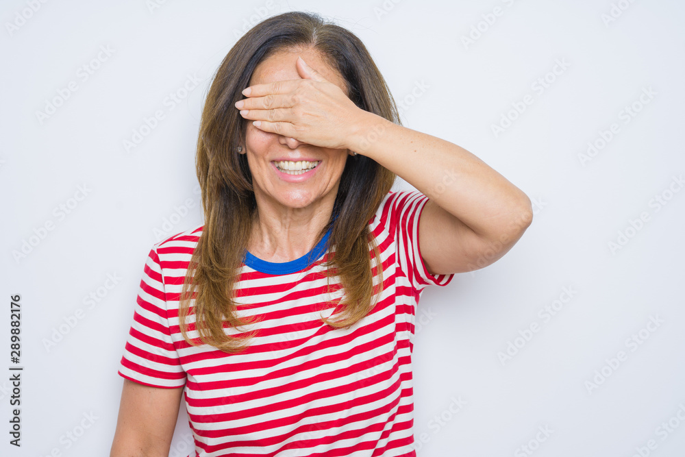 Middle age senior woman standing over white isolated background smiling and laughing with hand on face covering eyes for surprise. Blind concept. Middle age senior woman standing over white isolated background smiling and laughing with hand on face covering eyes for surprise. Blind concept.