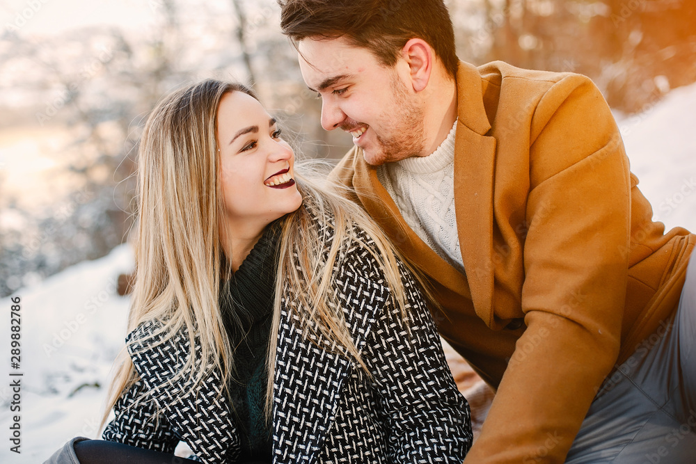 happy young couple having a picnic in the park on a snowy winter day