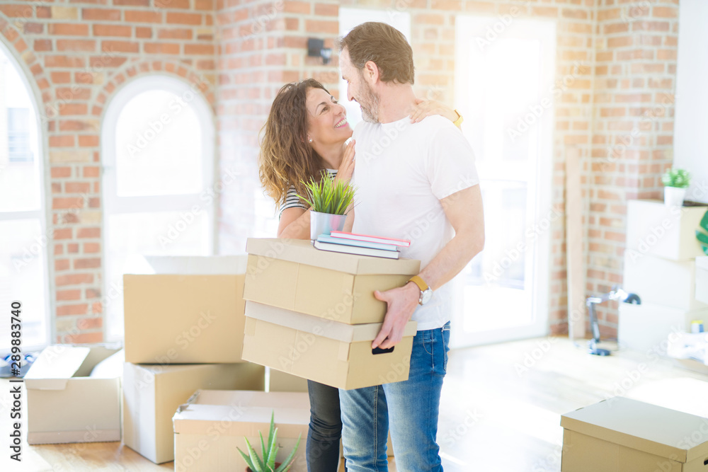 Middle age senior couple moving to a new house, holding cardboard boxing smiling happy in love with apartmant Middle age senior couple moving to a new house, holding cardboard boxing smiling happy in love with apartmant