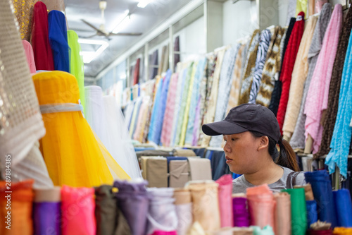 Asian woman selecting many kinds of cloth in fabric shop