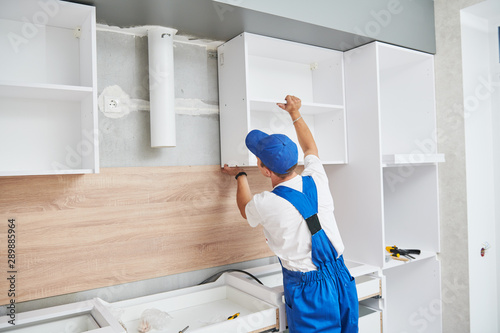 Fotografie kitchen installation. Worker assembling furniture
