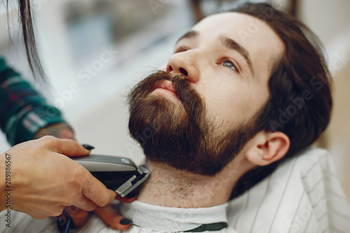 Man with a beard. Hairdresser with a client. Woman with a comb and shaving machine