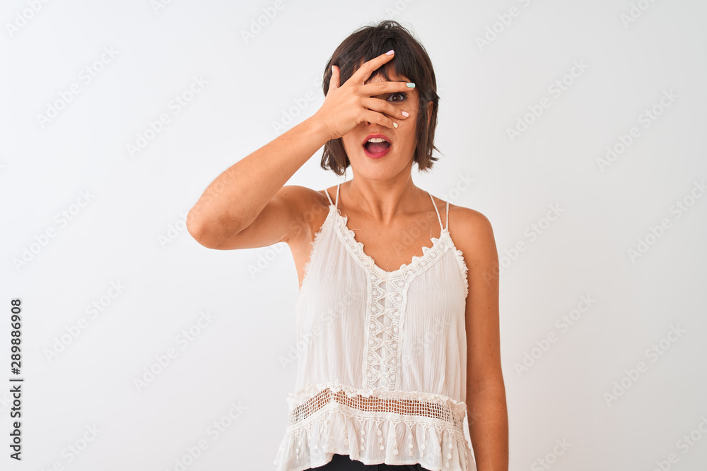 Young beautiful woman wearing summer casual t-shirt standing over isolated white background peeking in shock covering face and eyes with hand, looking through fingers with embarrassed expression. Young beautiful woman wearing summer casual t-shirt standing over isolated white background peeking in shock covering face and eyes with hand, looking through fingers with embarrassed expression.
