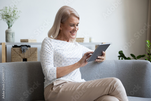Smiling mature woman using computer tablet at home