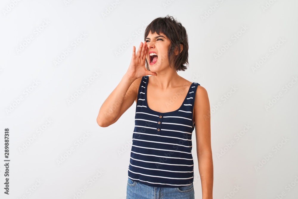 Young beautiful woman wearing striped t-shirt standing over isolated white background shouting and screaming loud to side with hand on mouth. Communication concept. Young beautiful woman wearing striped t-shirt standing over isolated white background shouting and screaming loud to side with hand on mouth. Communication concept.