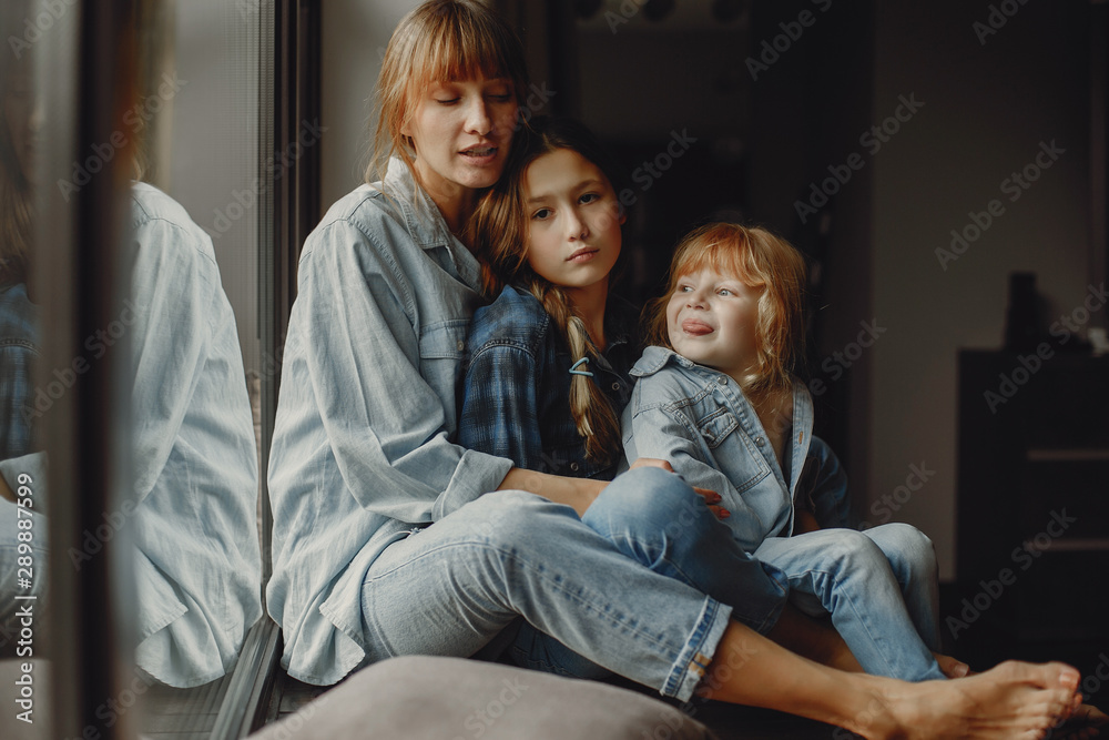 Beautiful mother with two daughters. Family sitting in the room near window Beautiful mother with two daughters. Family sitting in the room near window