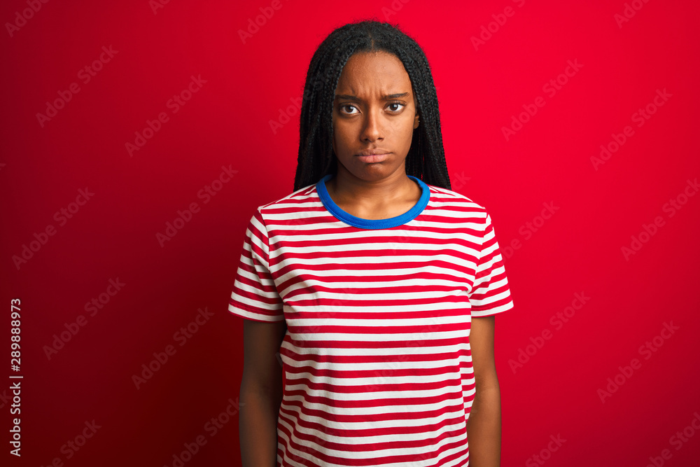 Young african american woman wearing striped t-shirt standing over isolated red background depressed and worry for distress, crying angry and afraid. Sad expression. Young african american woman wearing striped t-shirt standing over isolated red background depressed and worry for distress, crying angry and afraid. Sad expression.
