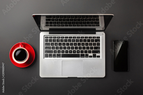 Elegant black office desktop with laptop, cup of coffee and mobile phone