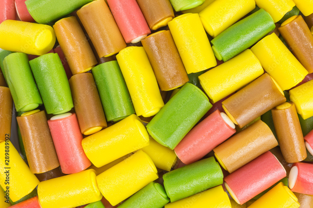 background of gummy rolls in yellow, pink, green and brown background of gummy rolls in yellow, pink, green and brown