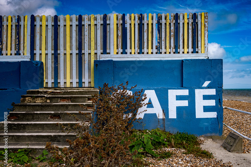 Blue beach cafe sign with multicoloured fence © J-F Phillips