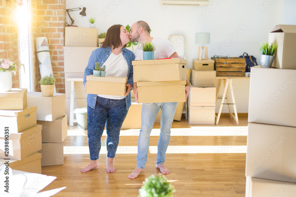 Young couple moving to a new home, smiling happy holding cardboard boxes Young couple moving to a new home, smiling happy holding cardboard boxes